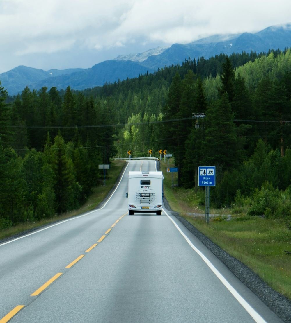 Motorhome driving on an empty road through a forest